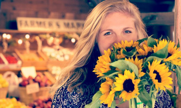 woman in blue and white floral top holding sunflower buoquet